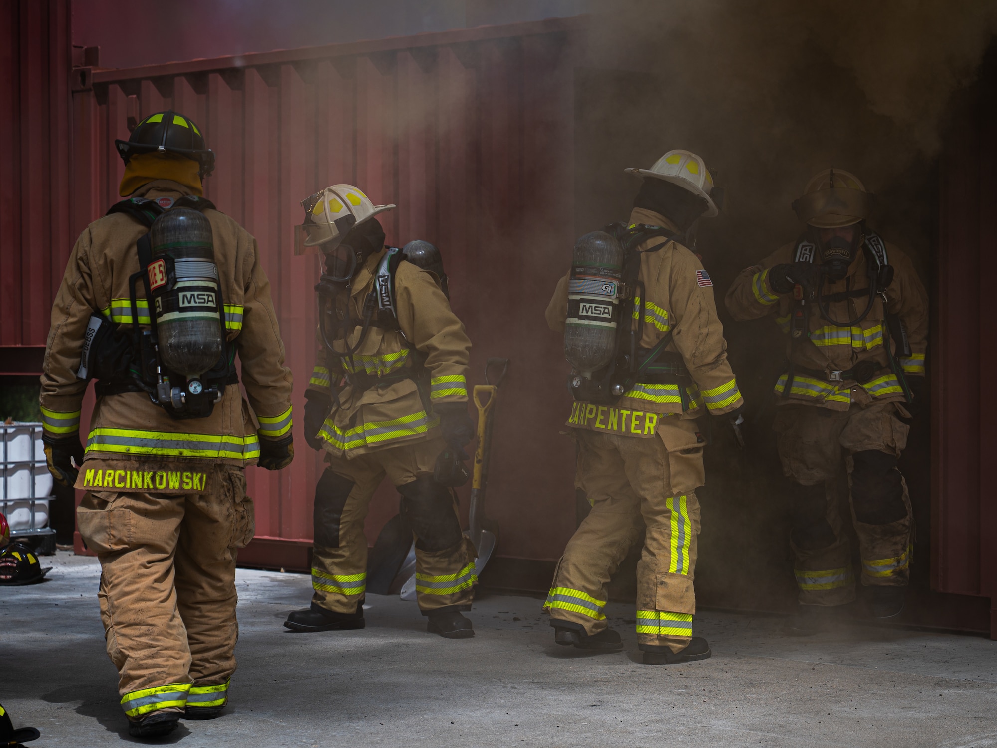 A photo of four firefighters exiting a room full of smoke.
