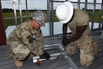 Airmen from the 159th Civil Engineering Squadron, Louisiana Air National Guard, assemble a door frame for installation inside a fire training tower at Volk Field Combat Readiness Training Center, Camp Douglas, Wisconsin, July 21, 2026. The squadron participated in a multi-unit construction project in which each Air National Guard civil engineering squadron completed a portion of the tower before transferring the project to the next unit. Photo by Senior Airman Jacob Hall.