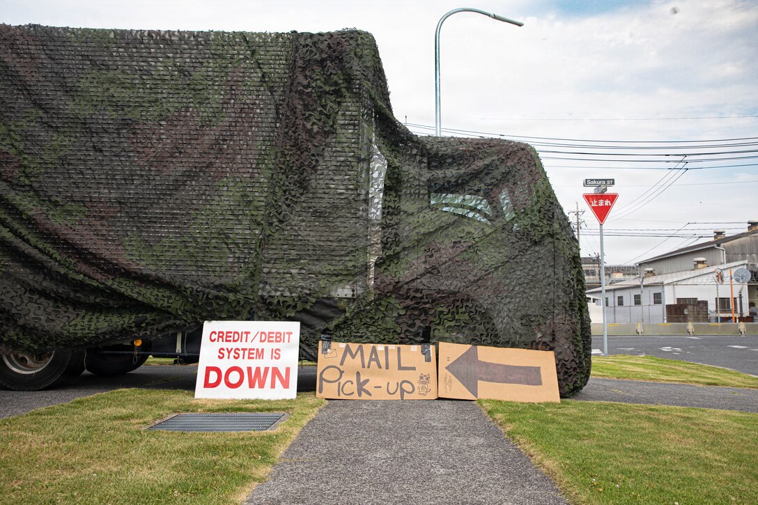 A box truck is staged under camouflage netting with a mail pickup sign during an annual postal deployment training exercise at Marine Corps Air Station Iwakuni, Japan, July 17, 2026. MCAS Iwakuni postal services conducted an annual pre-deployment training to practice expeditionary mail operations in a simulated field environment. (U.S. Marine Corps photo by Lance Cpl. Donald Dugger)