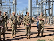 16th Air Force leadership stands in front of an electric grid.