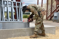 Airman 1st Class Angel Rodriguez De Leon, 159th Civil Engineering Squadron, Louisiana Air National Guard, constructs end caps used to fasten walls to supporting beams on a fire training tower at Volk Field Combat Readiness Training Center, Camp Douglas, Wisconsin, July 21, 2026.