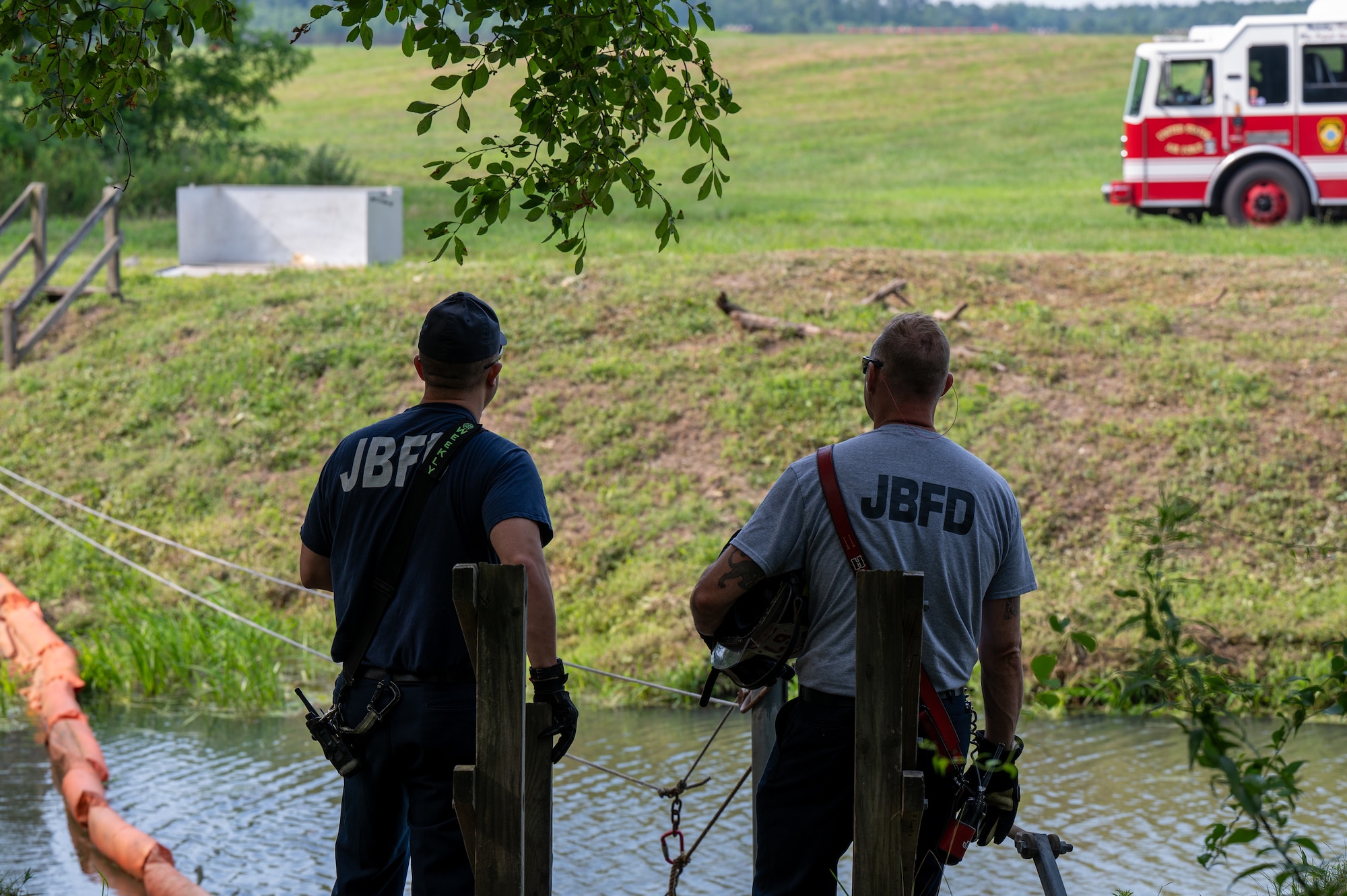 Joint Base Fire Department firefighters stand near a waterway during a spill response exercise at Joint Base McGuire-Dix-Lakehurst, N.J., July 15, 2026.