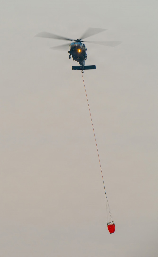 An Oregon Army National Guard HH-60M Black Hawk helicopter returns to Army Aviation Support Facility #2 in Pendleton, Oregon, carrying a water bucket, July 29, 2026, in support of wildland firefighting operations on the Hagen Fire in Umatilla County.