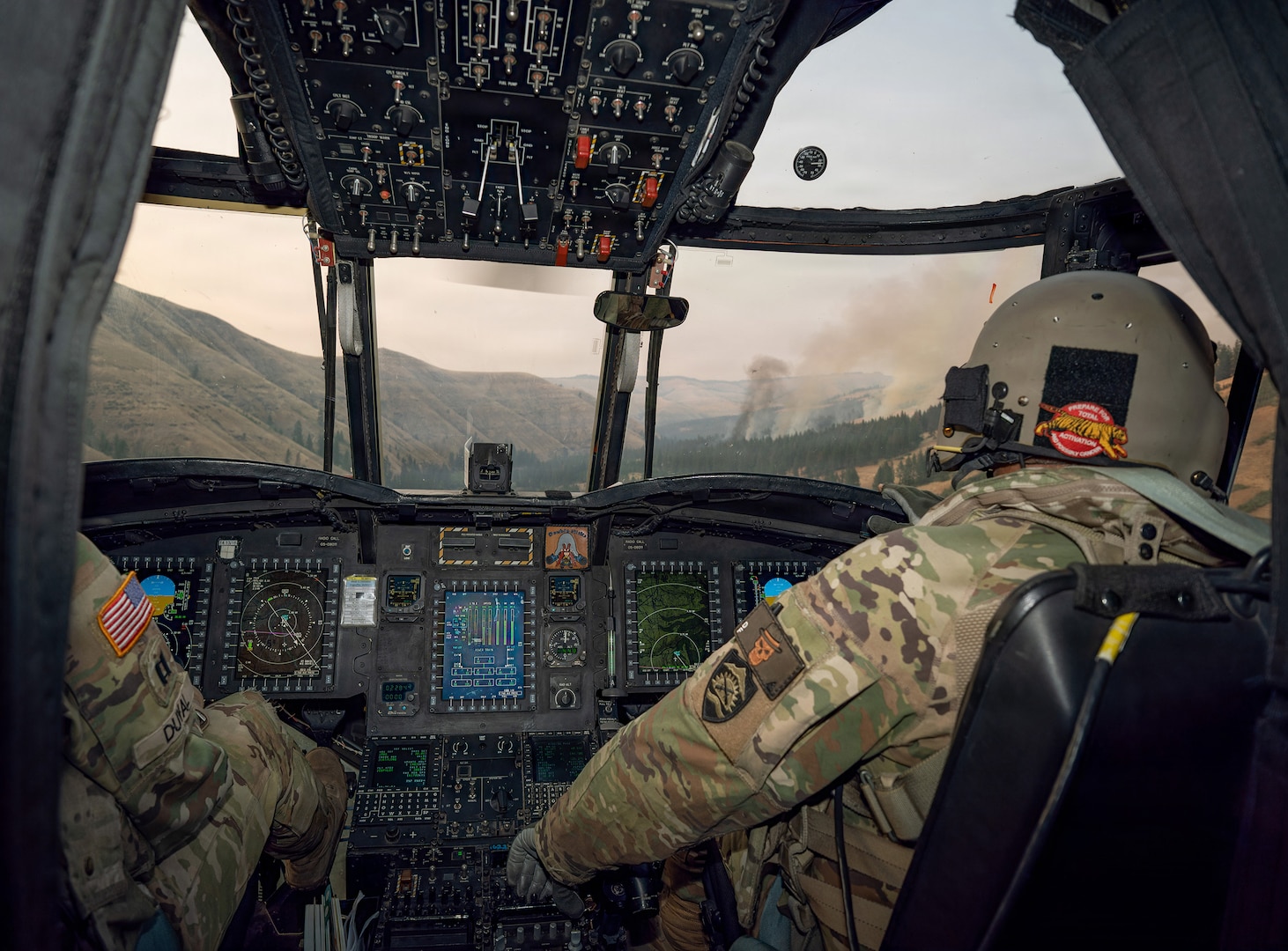 U.S. Army Chief Warrant Officer 5 Donald Ford, right, and Capt. Richard Duval pilot a CH-47 Chinook helicopter toward the Hagen Fire in Umatilla County, Oregon, July 29, 2026, during water bucket operations in support of Oregon's wildfire response.