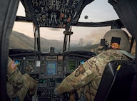 U.S. Army Chief Warrant Officer 5 Donald Ford, right, and Capt. Richard Duval pilot a CH-47 Chinook helicopter toward the Hagen Fire in Umatilla County, Oregon, July 29, 2026, during water bucket operations in support of Oregon's wildfire response.