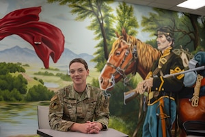 Staff Sgt. Sara Hallstein, Intelligence Support Squadron noncommissioned officer in charge, poses for a photo next to a mural she painted at Wright-Patterson Air Force Base, Ohio, June 25, 2026. Through her art, Hallstein hopes to encourage others to uncover their own "hidden gifts" and redefine how creativity fits into the broader National Air and Space Intelligence Center mission. (U.S. Air Force photo by Staff Sgt. Kristof J. Rixmann)