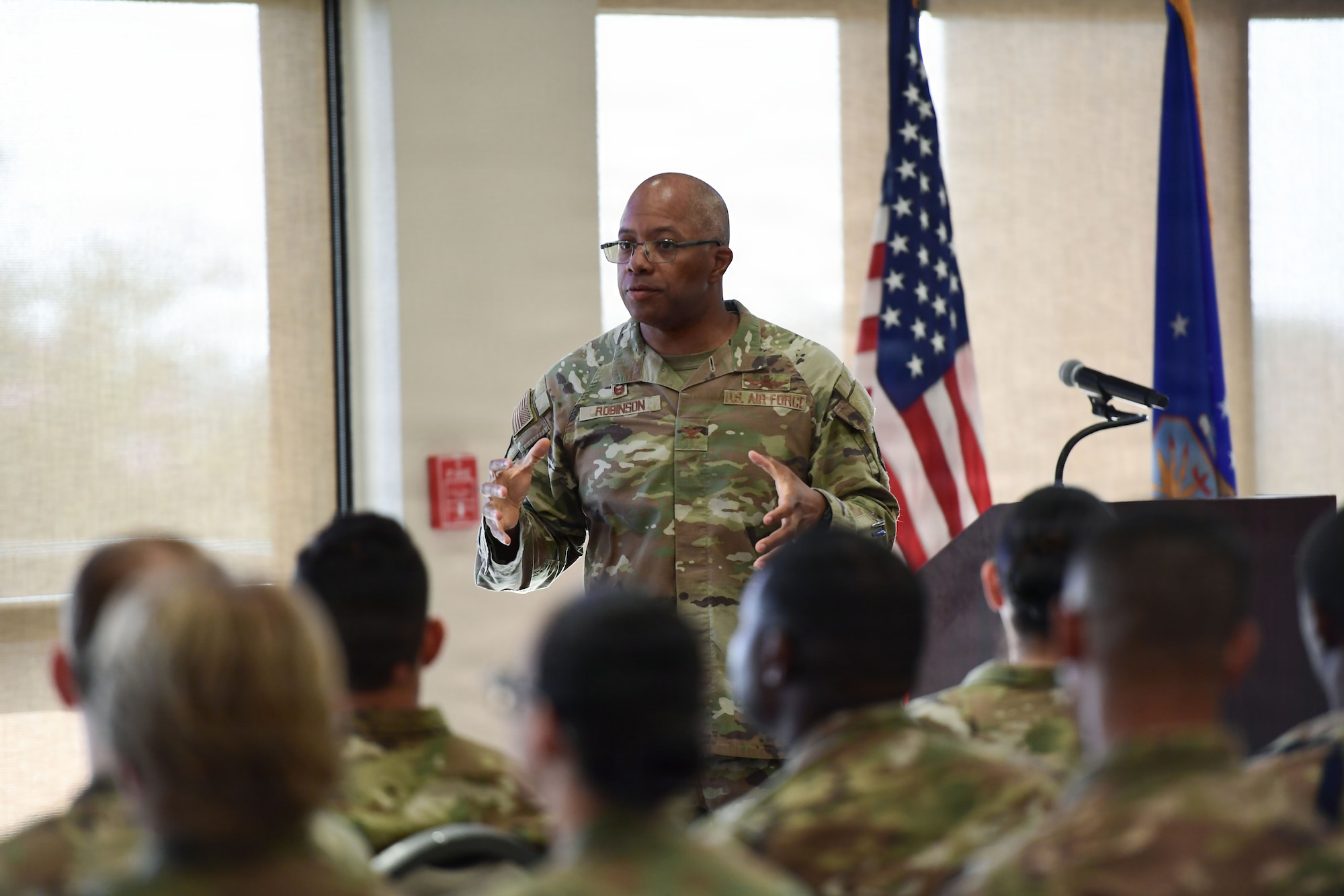 A man in a U.S. Air Force uniform speaks to a crowd of Airmen.