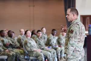 A man in a U.S. Air Force uniform speaks to a crowd of Airmen.