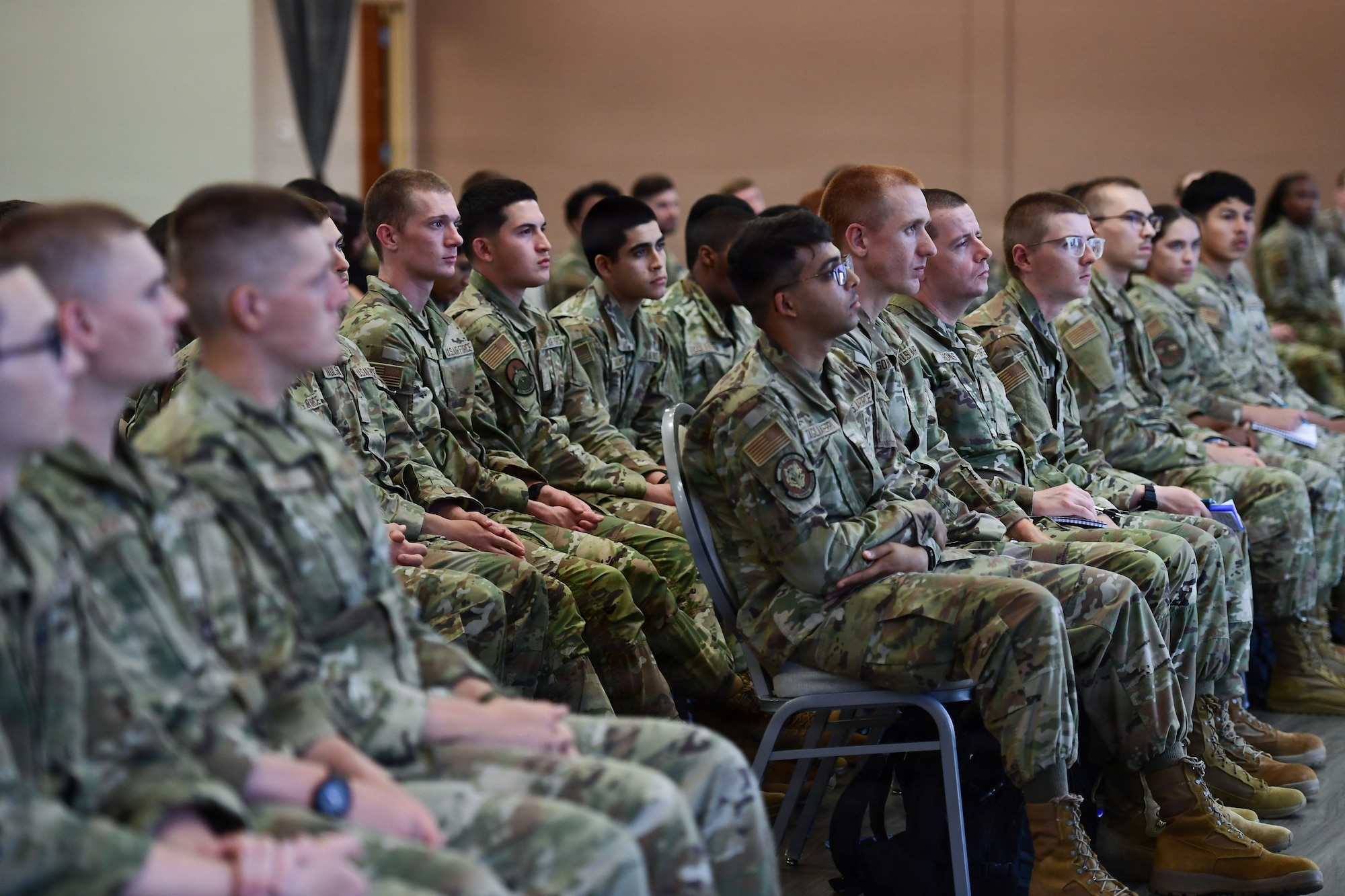 A group of Airmen sit in an audience.