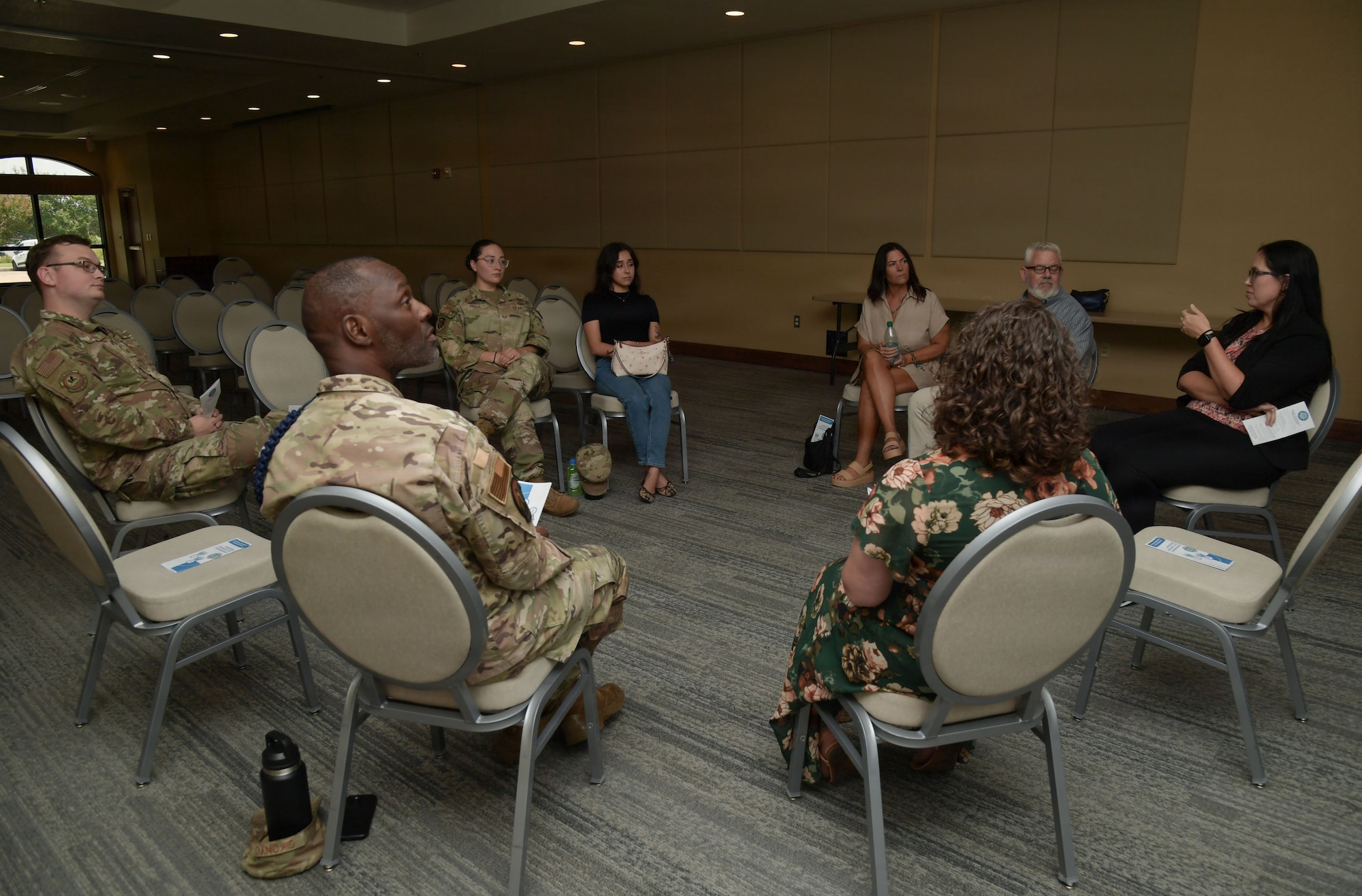 A group of people sit around in a circle during discussion.