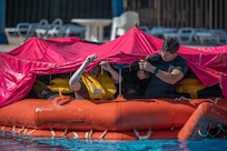Senior Airman Martin Palomino, a 552nd Operations Support Squadron survival, evasion, resistance and escape specialist, works with Airmen to secure a canopy over a life raft during water survival training at Altus Air Force Base, Okla., July 10, 2026. SERE specialists led the Airmen as they practiced properly securing the canopy to the raft. (U.S. Air Force photo by Airman 1st Class Emma Wright)