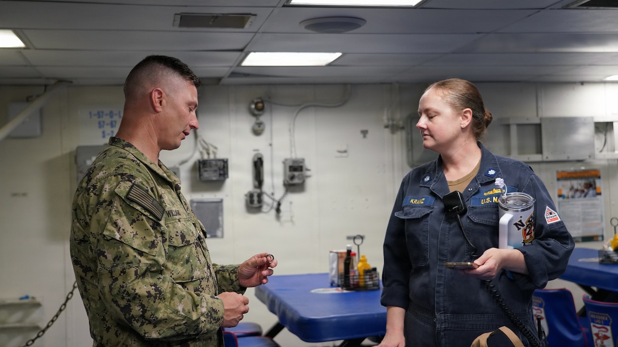 JOINT BASE PEARL HARBOR-HICKAM, Hawaii (June 26, 2026) Lt. Cmdr. Brian Williams of Naval Health Research Center (NHRC) discusses wearable devices capabilities with USS Essex (LHD-2) operations officer, Cmdr. Julia Kranz. Roughly 200 sailors aboard the Essex have been provided with an Oura Ring to track physiological data in order to inform illness prediction algorithms while participating in the Rim of the Pacific (RIMPAC) exercise. Thirty-one nations, 36 surface ships, 5 submarines, 15 national land forces, more than 206 aircraft and 25,000 personnel are participating in RIMPAC in and around the Hawaiian Islands, June 24 to July 31. The world's largest international maritime exercise, RIMPAC provides a unique training opportunity while fostering and sustaining cooperative relationships among participants critical to ensuring the safety of sea lanes and security on the world's oceans. RIMPAC 26 is the 30th exercise in the series that began in 1971. (U.S. Navy photo by Danielle Cazarez/Released)