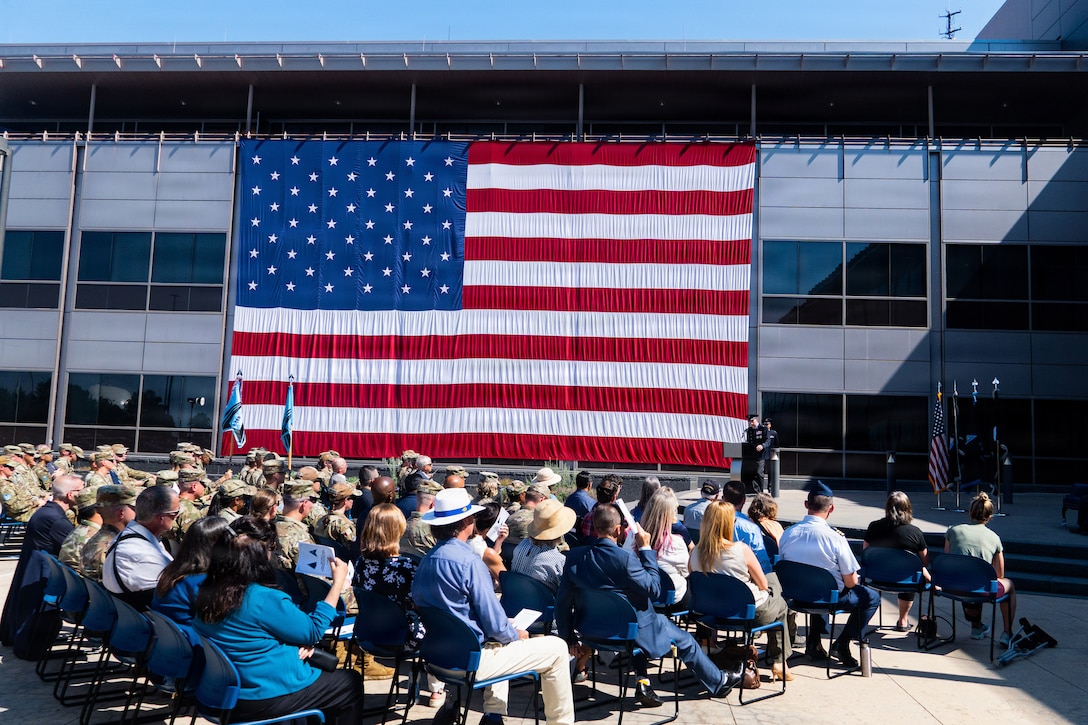 Change of command ceremony. People in uniform, & flags.