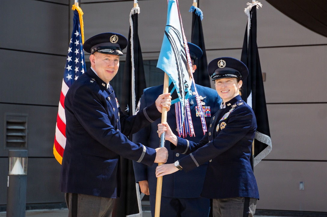 Change of command ceremony. People in uniform, & flags.