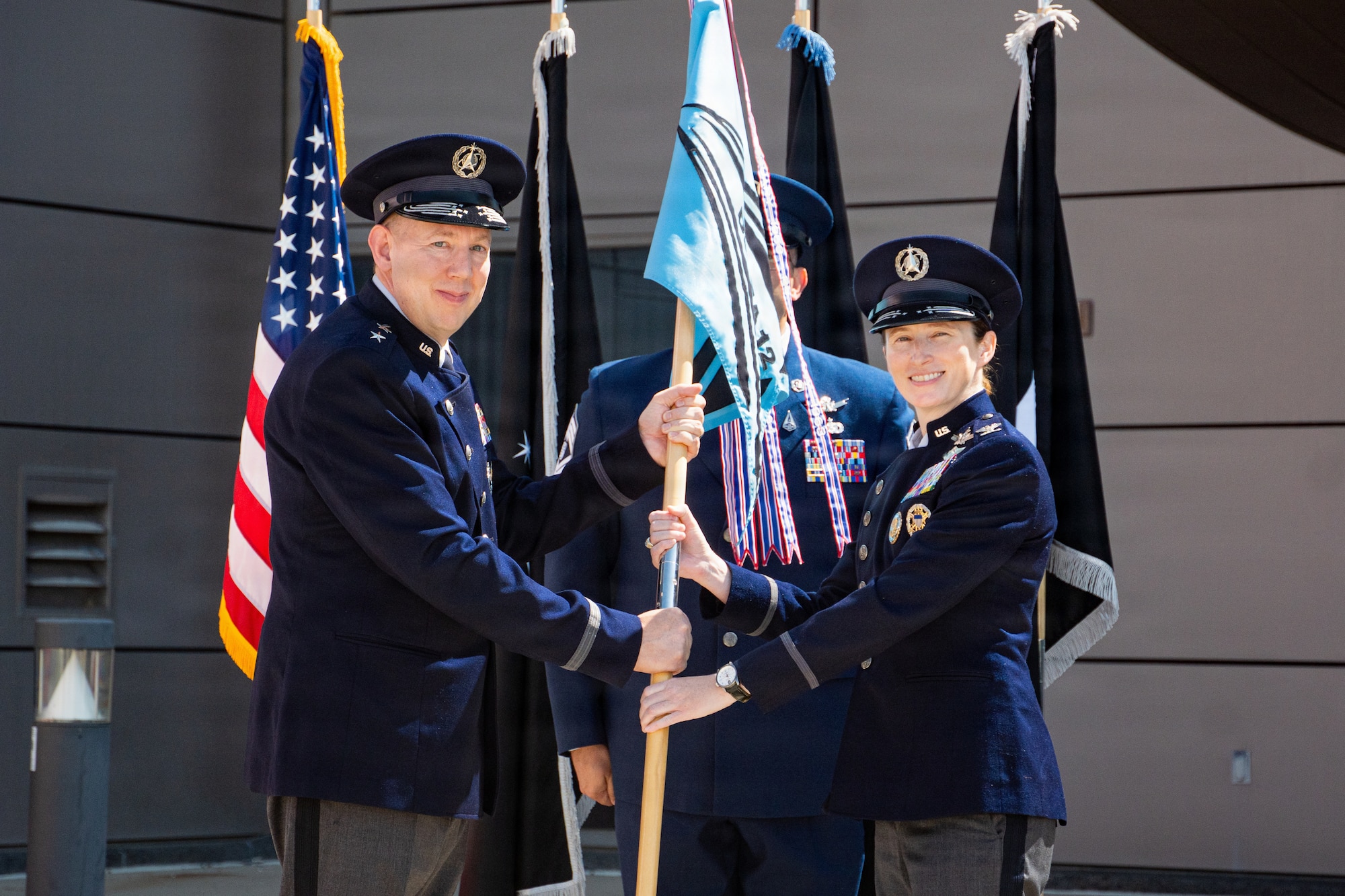 Change of command ceremony. People in uniform, & flags.