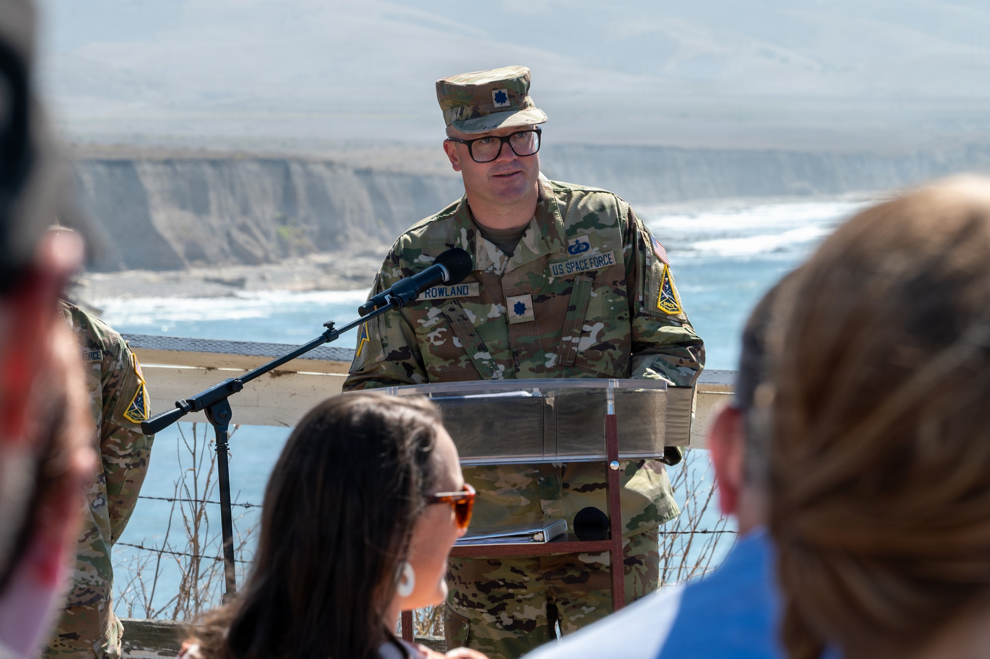 A person stands and speaks behind a podium outside