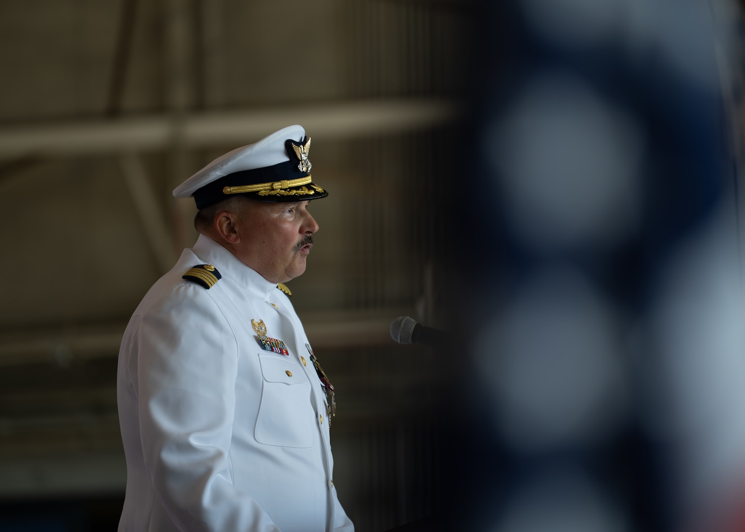 U.S. Coast Guard Capt. Bradford Apitz addresses an audience during a change of command ceremony at Air Station Sacramento, McClellan Park, California, July 31, 2026. During the ceremony, Coast Guard Capt. Patrick Dill was formally recognized as the new air station commander. (U.S. Coast Guard photo by Petty Officer 3rd Class Kenneth Wiese)