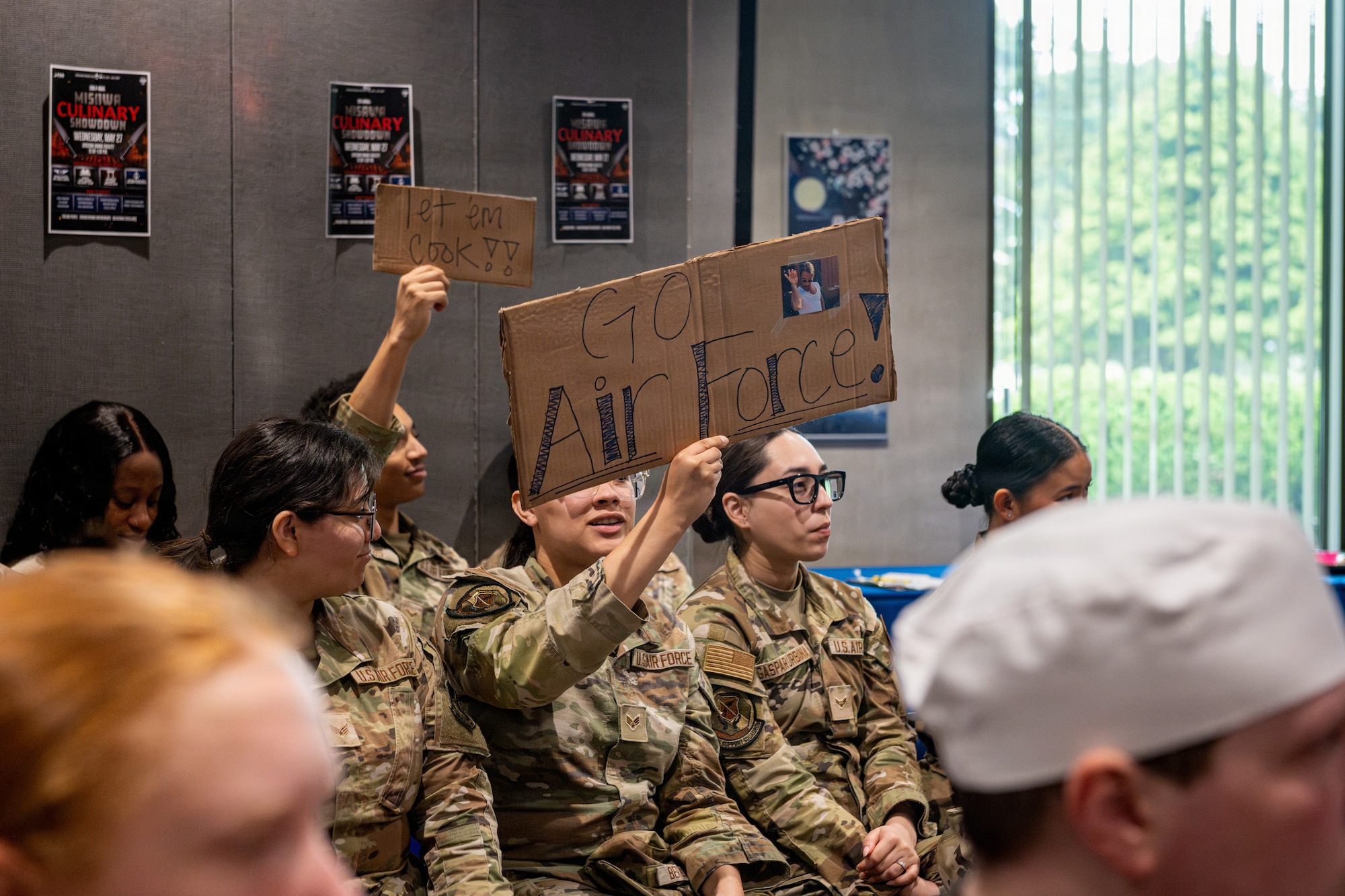 U.S. Airmen assigned to the 35th Force Support Squadron support their fellow Airmen from the crowd during a culinary competition.