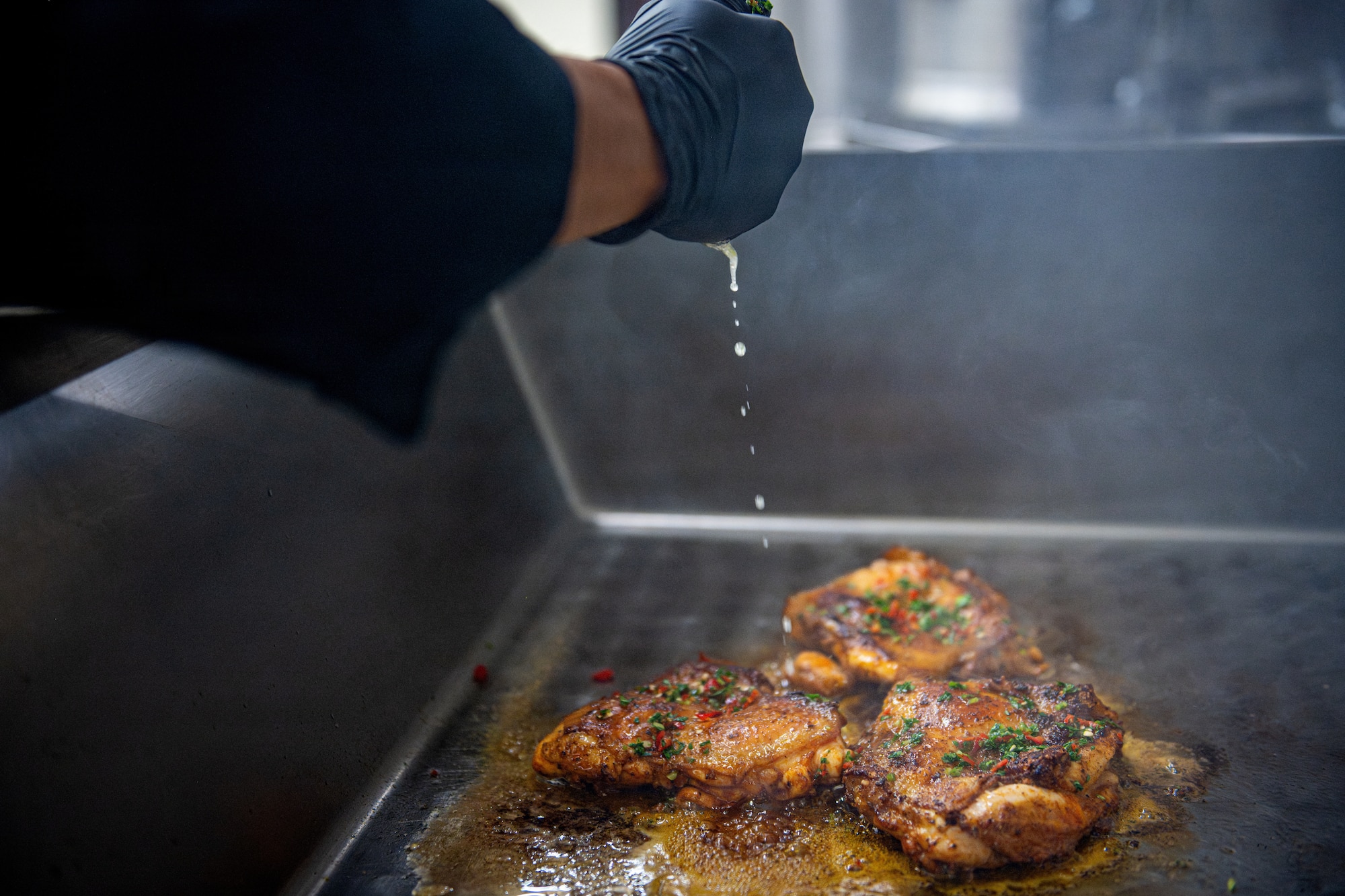 U.S. Air Force Airman 1st Class Anh Vu, 35th Force Support Squadron food service apprentice, squeezes a lime onto chicken breasts.