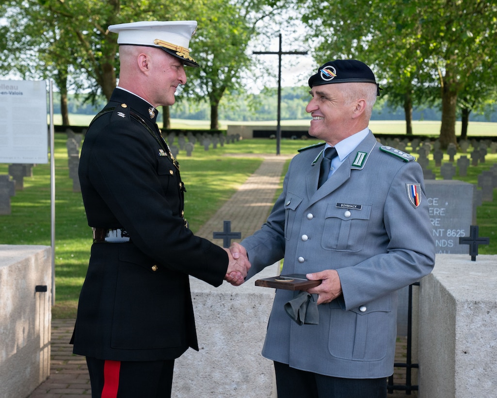 U.S. Marine Corps Maj. Gen. Daniel Shipley, commander, U.S. Marine Corps Forces Europe and Africa, exchanges gifts with German Col. Heiko Bohnsack, Deputy Commander of the Franco-German brigade at the German Military Cemetery in Chateau-Thierry, France, May 23, 2026. Shilpey and Bohnsack exchanged the gifts after completing the German Military Cemetery memorial ceremony. Established in 2018 as an addition to the traditional Memorial Day ceremonies in Château-Thierry, the German Military Cemetery memorial ceremony commemorated the 108th anniversary of the Battle of Belleau Wood. While the observance honors the legacy of service members who gave their lives in defense of the United States and its European partners, it also serves as a solemn testament to the power of reconciliation.  The ceremony is given with deep respect for the former adversaries, recognizing that the German nation—once a foe on these historic battlefields—has long since stood alongside us as a steadfast and enduring ally. (U.S. Marine Corps photo by Gunnery Sgt. Donato Maffin)