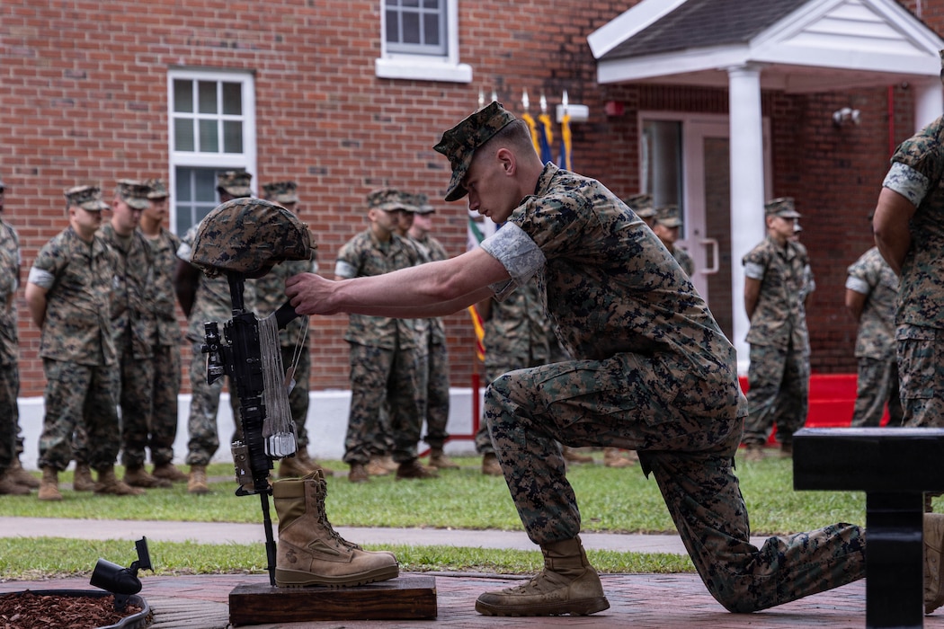 U.S. Marine Corps Sgt. Matthew Goodwin, an intelligence analyst with 2nd Light Reconnaissance Battalion, 2nd Marine Division, places a dog tag on the battle cross during a memorial ceremony on Marine Corps Base Camp Lejeune, North Carolina, May 22, 2026. The memorial service paid tribute to the 28 Marines and Sailor who made the ultimate sacrifice in combat, while commemorating the battalion’s historic achievements from 1989 to 2011. (U.S. Marine Corps photo by Cpl. Judith Ann Lazaro)