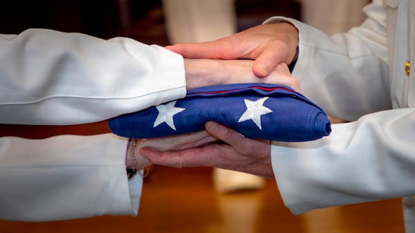 Lt. Mary Hopkins, assigned to Naval Medical Forces Atlantic (NMFL), passes an United States Flag to Lt. Cmdr. Scott Woodson, assigned to NMFL, during Capt. Chad McKenzie’s, a native of Bellefontaine, Ohio, retirement ceremony on board Naval Support Activity (NSA) Hampton Roads - Portsmouth Annex, Portsmouth, Virginia, May 29, 2026. McKenzie served the Navy for nearly 30 years of dedicated service across 16 commands and helped advance Navy Medicine’s operational readiness and expeditionary medical capabilities in support of Fleet, Marine Corps, and joint force requirements. (U.S. Navy photo by Mass Communication Specialist 2nd Class Levi Decker)