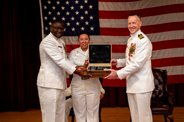 Naval Medical Forces Atlantic (NMFL) Command Master Chief Lamar Bethel, presents a gift from NMFL’s Chiefs Mess to Capt. Chad McKenzie, deputy commander, NMFL and a native of Bellefontaine, Ohio, during his retirement ceremony on board Naval Support Activity (NSA) Hampton Roads - Portsmouth Annex, Portsmouth, Virginia, May 29, 2026. McKenzie served the Navy for nearly 30 years of dedicated service across 16 commands and helped advance Navy Medicine’s operational readiness and expeditionary medical capabilities in support of Fleet, Marine Corps, and joint force requirements.  (U.S. Navy photo by Mass Communication Specialist 2nd Class Levi Decker)