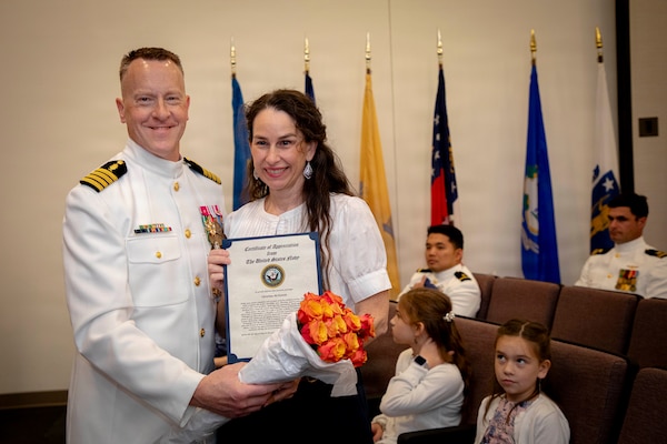 Naval Medical Forces Atlantic Command Deputy Commander, Capt. Chad McKenzie,  a native of Bellefontaine, Ohio, presents his family with certificates of appreciation during his retirement ceremony on board Naval Support Activity (NSA) Hampton Roads - Portsmouth Annex, Portsmouth, Virginia, May 29, 2026. McKenzie served the Navy for nearly 30 years of dedicated service across 16 commands and helped advance Navy Medicine’s operational readiness and expeditionary medical capabilities in support of Fleet, Marine Corps, and joint force requirements. (U.S. Navy photo by Mass Communication Specialist 2nd Class Levi Decker)