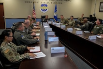 USAF Airmen and civilians sit at a conference room table