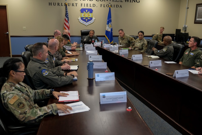 USAF Airmen and civilians sit at a conference room table