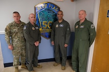 photo of four USAF Airmen standing in front of Blue Flag sign