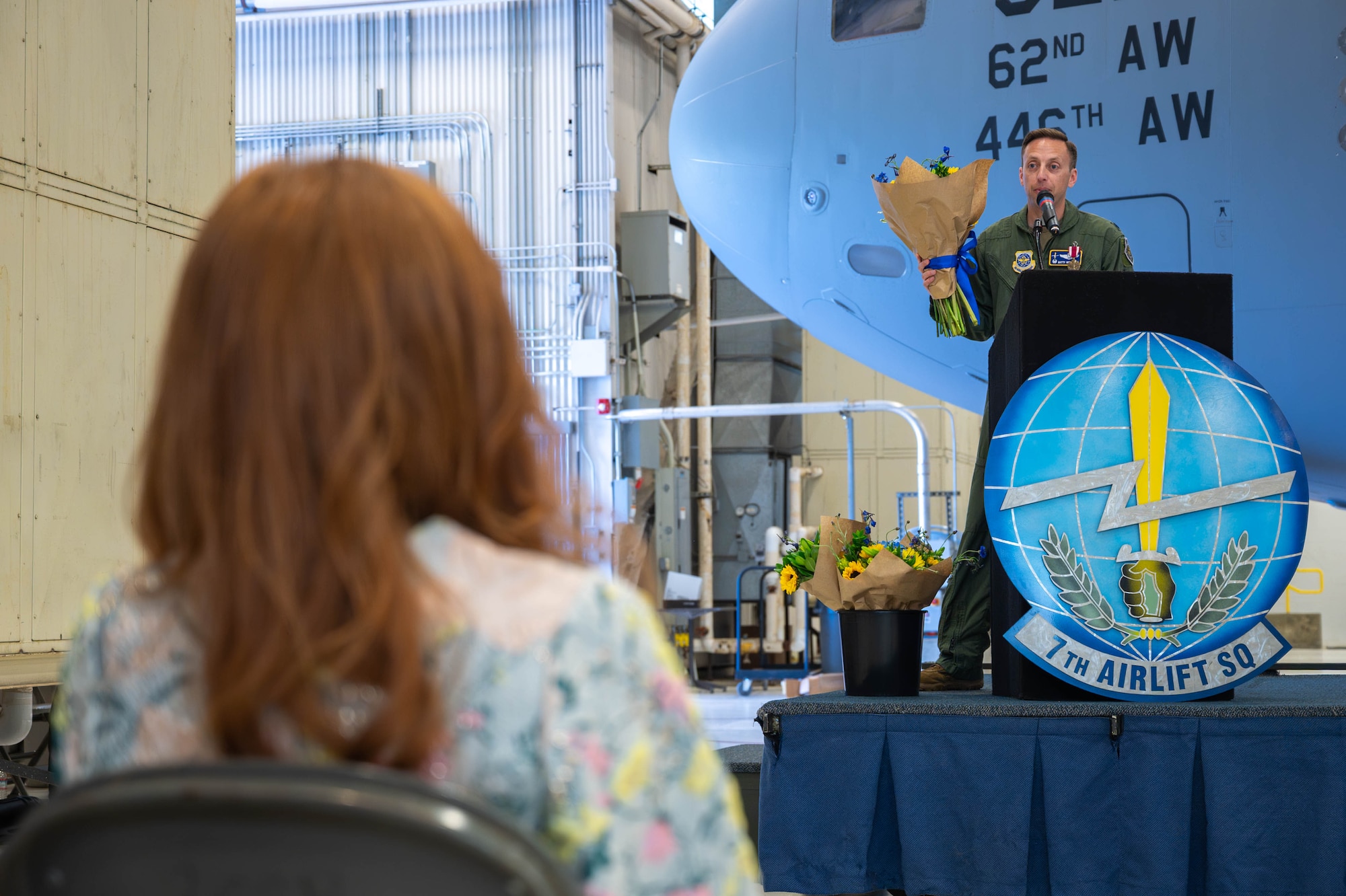 A man presents flowers from a stage.