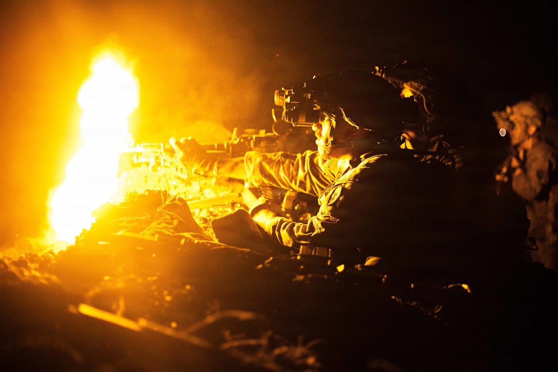 Two soldiers fire a weapon in the dark, creating an orangish fireball.