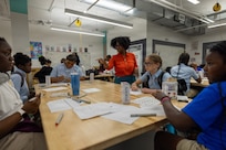 BALTIMORE (May 20, 2026) – Jacquelyn Southerland, a member of the Naval Surface Warfare Center, Carderock Division’s Strategic Education Outreach Team, guides SEED School of Baltimore students through a hands-on coding exercise using an Ozobot Ari robot during a Tech Day event. The compact, programmable robot helps make computer science engaging, supporting the Carderock team's broader mission to spark curiosity in 158 middle school students and inspire the next generation of science, technology, engineering, and mathematics (STEM) professionals. (U.S. Navy photo by Aaron Thomas)