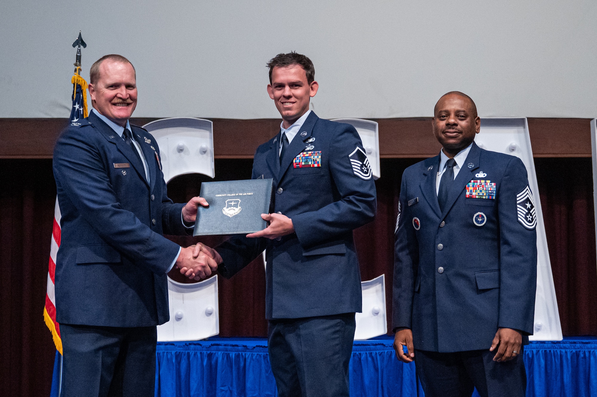 U.S. Air Force Master Sgt. Chad Carroll, 117th Logistics Readiness Squadron, receives his diploma from Col. Adam Rudolphi, left, 42d Air Base Wing deputy commander and Chief Master Sgt. Demetrius Booth, 42d ABW command chief, during a Community College of the Air Force graduation at Gunter Annex, Alabama, May 28, 2026.