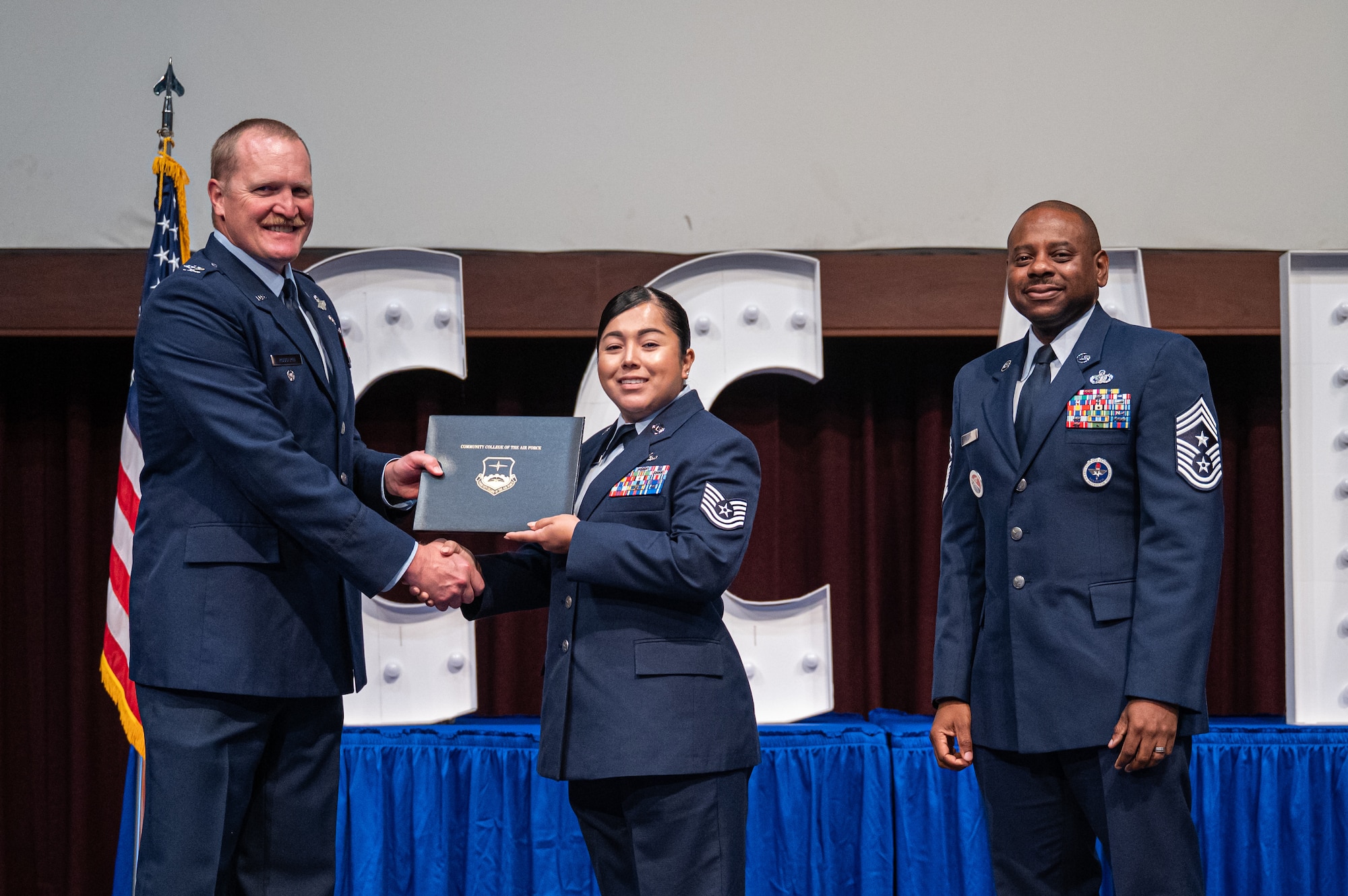 U.S Air Force Tech Sgt. Elizabeth Guinn, Air Education and Training Command Air War College receives her diploma from Col. Adam Rudolphi, left, 42d Air Base Wing deputy commander and Chief Master Sgt. Demetrius Booth, 42d ABW command chief, during a Community College of the Air Force graduation at Gunter Annex, Alabama, May 28, 2026.