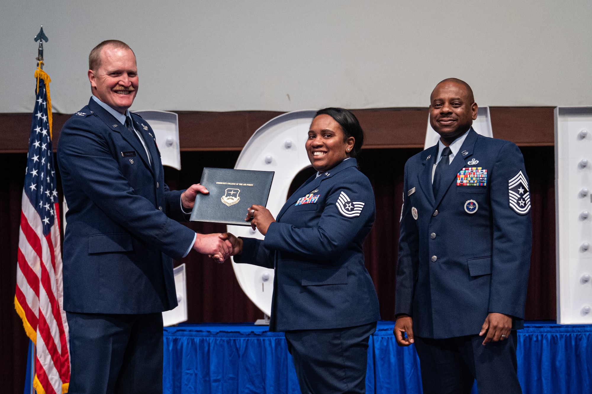 U.S. Air Force Tech Sgt. Anastasia Medina, 42d Force Support Squadron, receives her diploma from Col. Adam Rudolphi, left, 42d Air Base Wing deputy commander and Chief Master Sgt. Demetrius Booth, 42d ABW command chief, during a Community College of the Air Force graduation at Gunter Annex, Alabama, May 28, 2026.