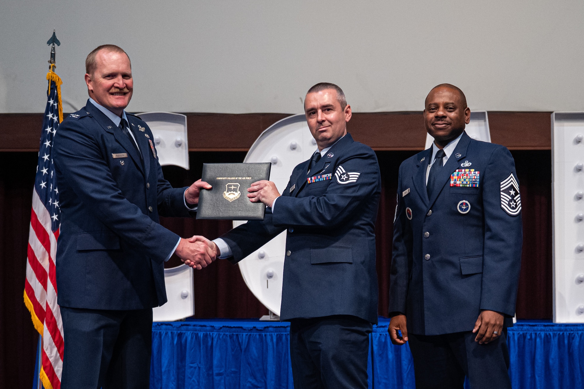 U.S. Air Force Staff Sgt. Brandon Simpson, Air Force Life Cycle Management Center, receives his diploma from Col. Adam Rudolphi, left, 42d Air Base Wing deputy commander and Chief Master Sgt. Demetrius Booth, 42 ABW command chief, during a Community College of the Air Force graduation at Gunter Annex, Alabama, May 28, 2026.