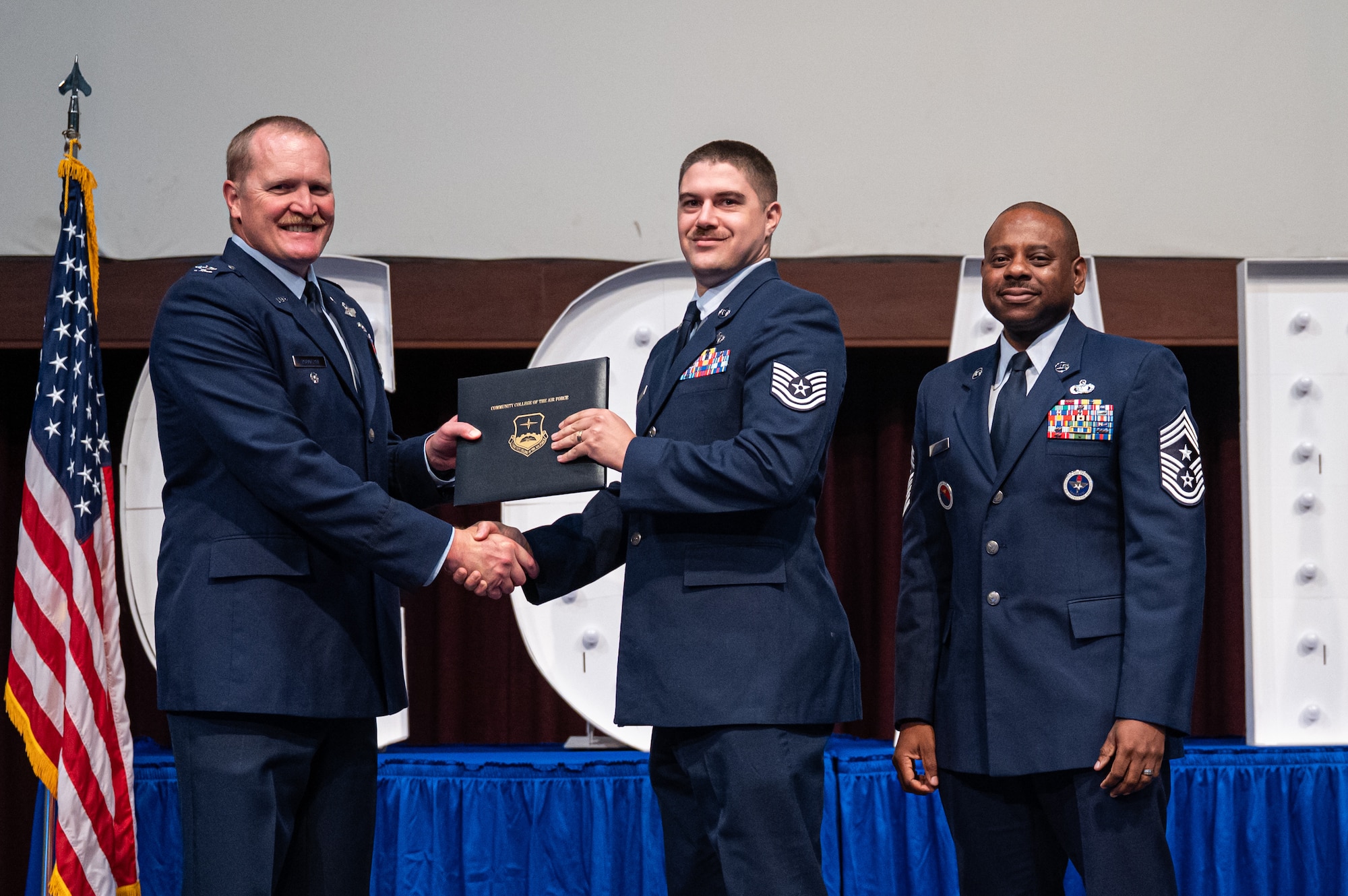 U.S. Air Force Tech Sgt. Alejandro Cebollero, 42d Force Support Squadron, receives his diploma from Col. Adam Rudolphi, left, 42d Air Base Wing deputy commander and Chief Master Sgt. Demetrius Booth, 42d command chief, May 28, 2026.