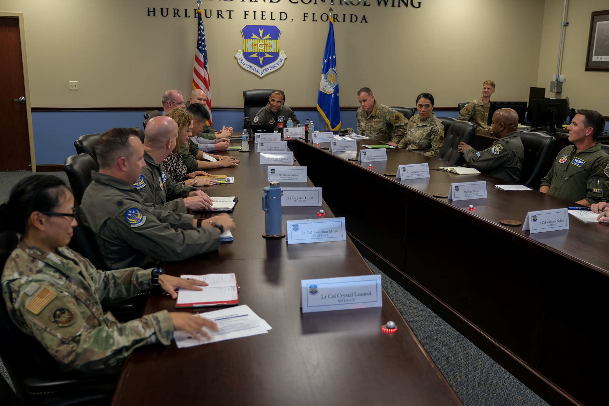 USAF Airmen and civilians sit at a conference room table