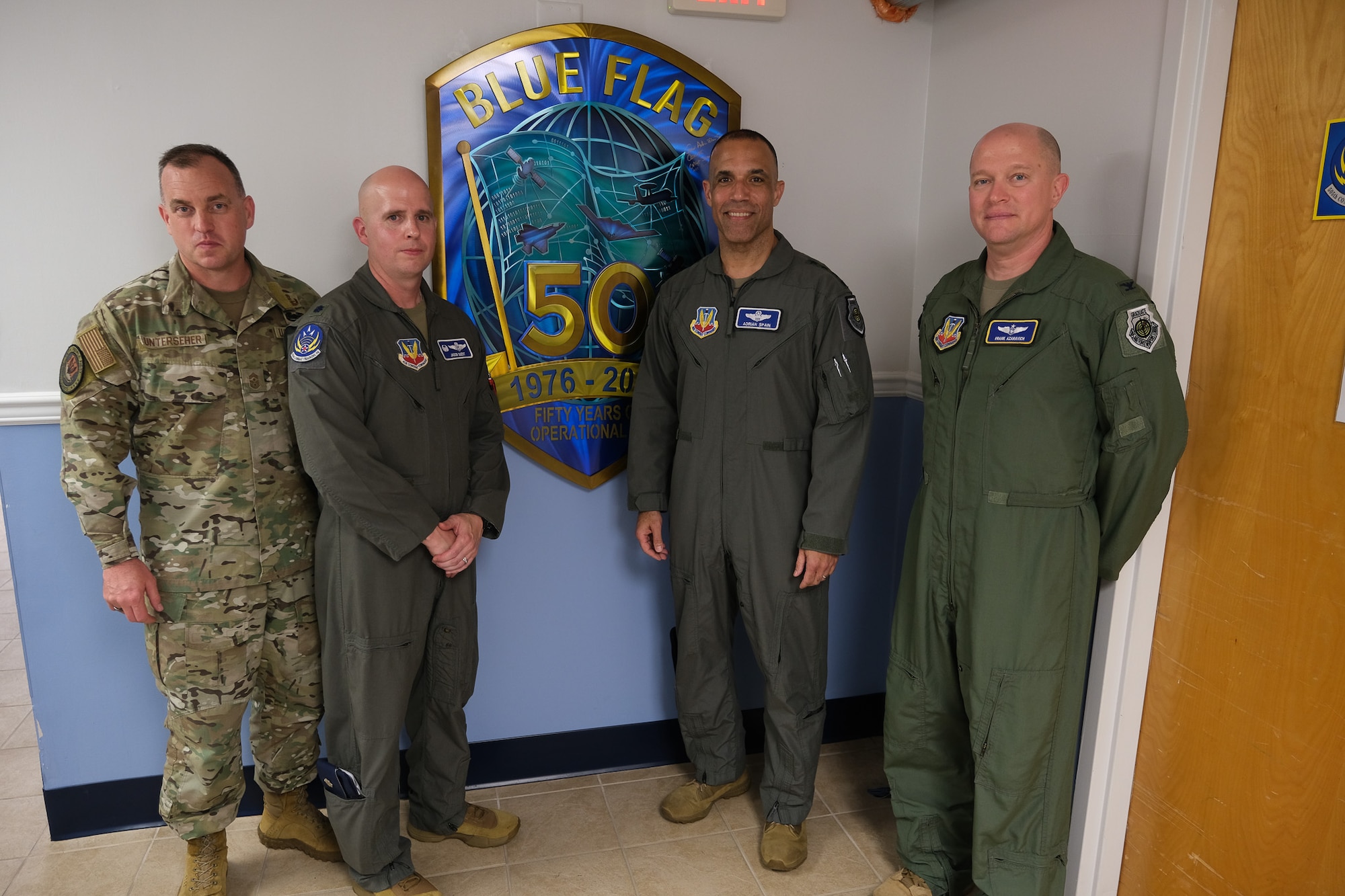 photo of four USAF Airmen standing in front of Blue Flag sign