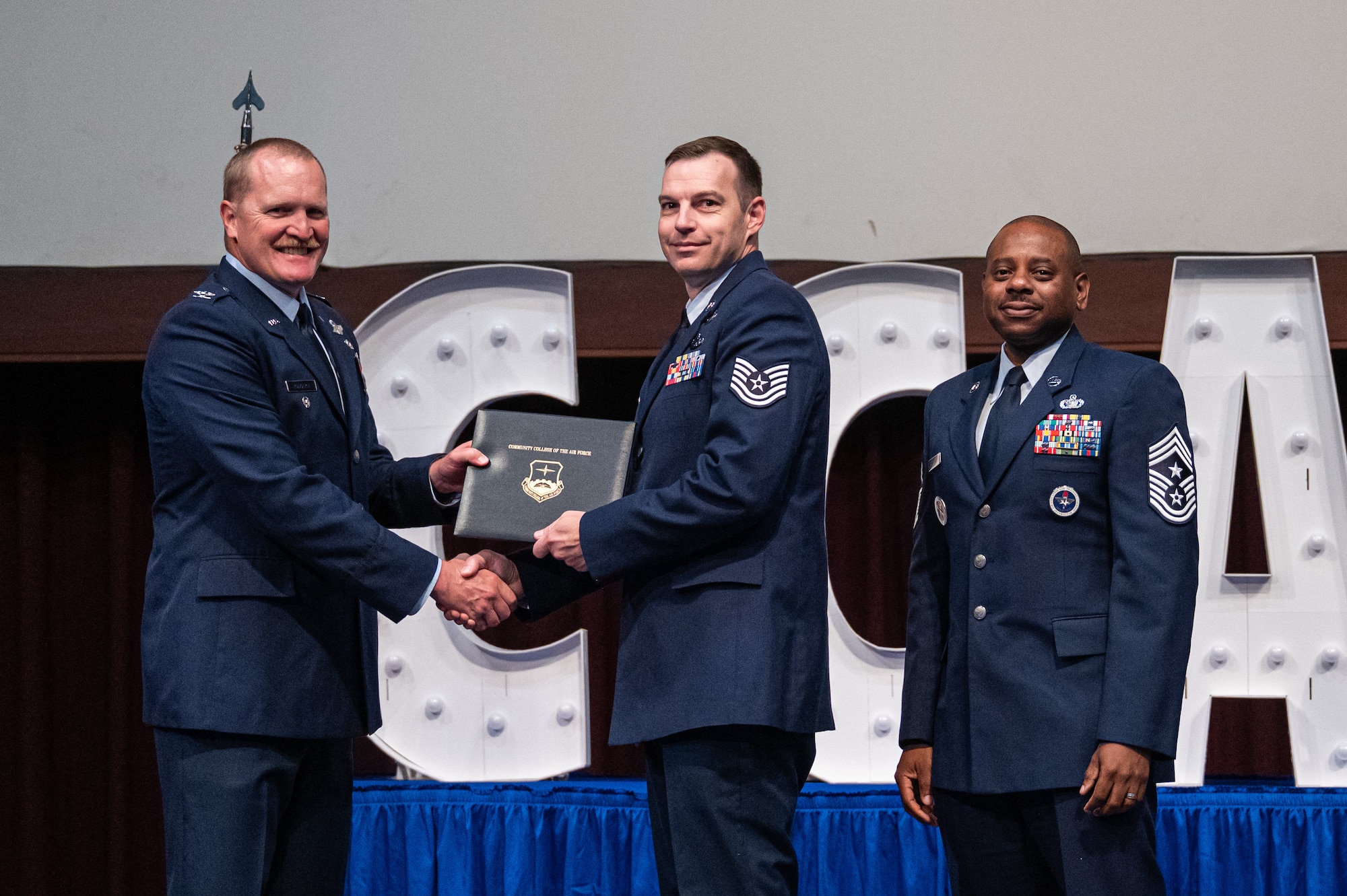 U.S. Air Force Tech Sgt. Adam Brewbaker, Air Force Reserve Officer Training Corps, receives his diploma from Col. Adam Rudolphi, left, 42d Air Base Wing deputy commander and Chief Master Sgt. Demetrius Booth, 42d ABW command chief, during a Community College of the Air Force graduation at Gunter Annex, Alabama, May 28, 2026.