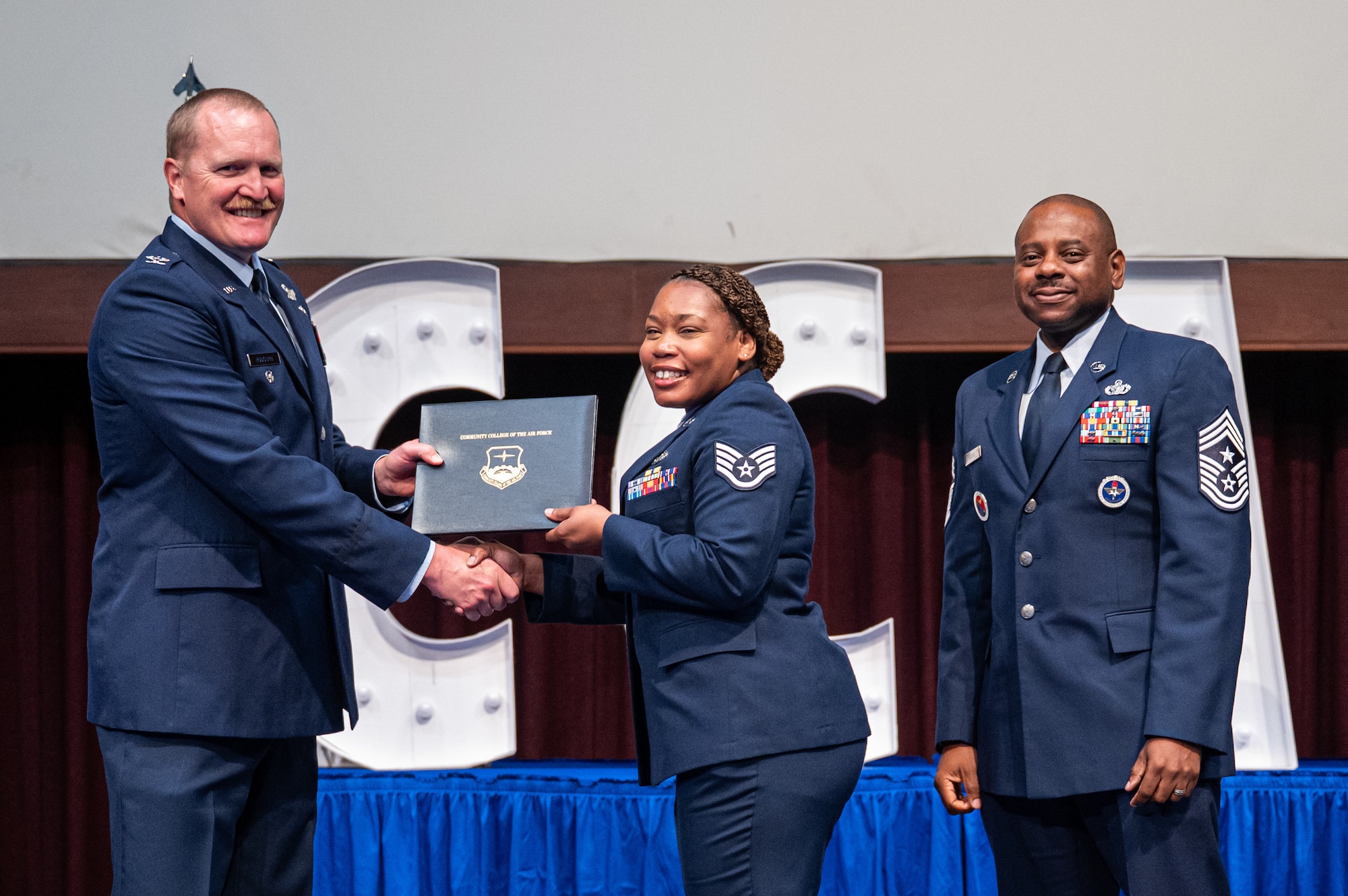 U.S. Air Force Staff Sgt. Alisia Chandler, 42d Contracting Squadron, receives her diploma from Col. Adam Rudolphi, left, 42d Air Base Wing deputy commander and Chief Master Sgt. Demetrius Booth, 42d ABW command chief, during a Community College of the Air Force graduation at Gunter Annex, Alabama, May 28, 2026.