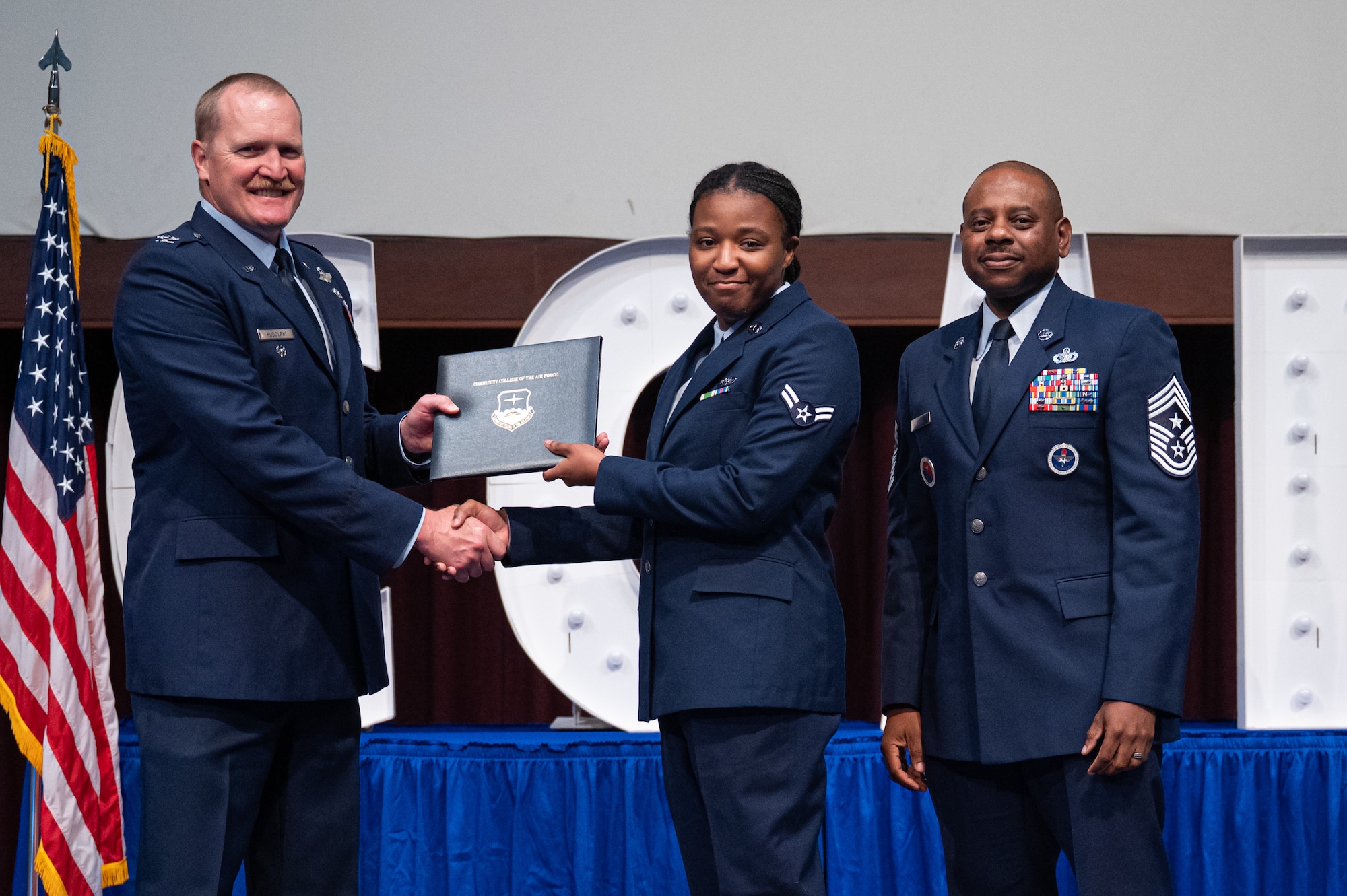 U.S. Air Force Naima White, Air Force Life Cycle Management, receives her diploma from Col. Adam Rudolphi, left, 42d Air Base Wing deputy commander and Chief Master Sgt. Demetrius Booth, 42d command chief, during a Community College of the Air Force graduation at Gunter Annex, Alabama, May 28, 2026.