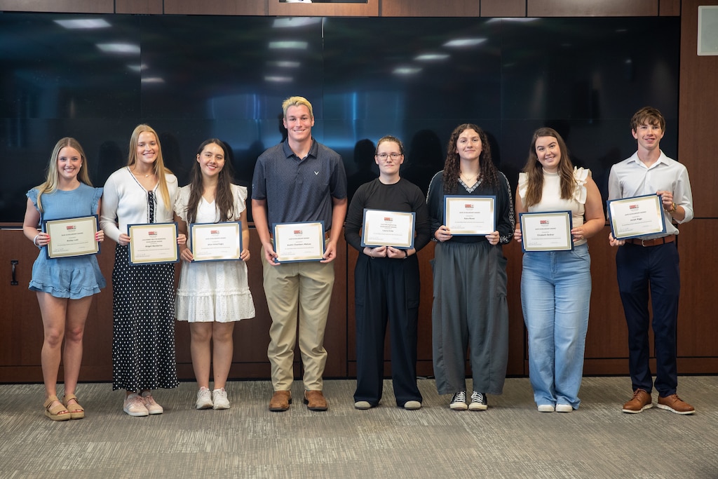 A group of recent high school grauates holding scholarship certificates.