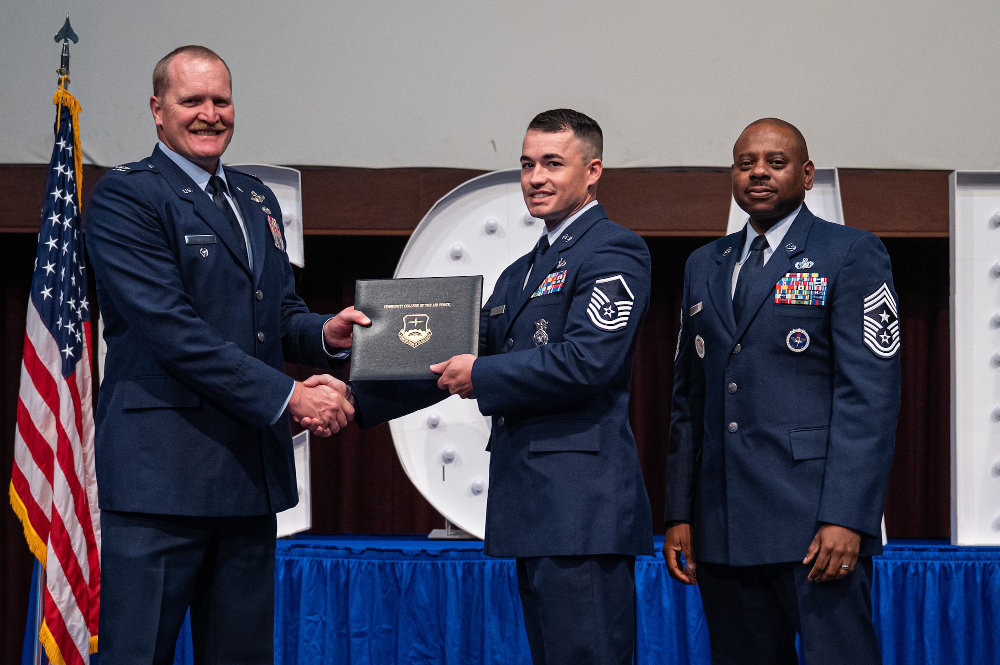 U.S. Air Force Master Sgt. Anthony Stevens, 117th Security Forces Squadron, receives his diploma from Col. Adam Rudolphi, left, 42d Air Base Wing deputy commander and Chief Master Sgt. Demetrius Booth, 42 ABW command chief, during a Community College of the Air Force graduation at Gunter Annex, Alabama, May 28, 2026.