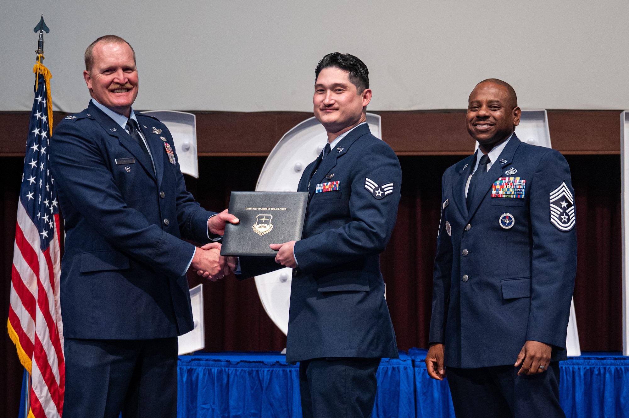 U.S Air Force Senior Airman Casey Money, 42d Force Support Squadron, receives his diploma from Col. Adam Rudolphi, left, 42d Air Base Wing deputy commander and Chief Master Sgt. Demetrius Booth, 42d ABW command chief, during a Community College of the Air Force graduation at Gunter Annex, Alabama, May 28, 2026.