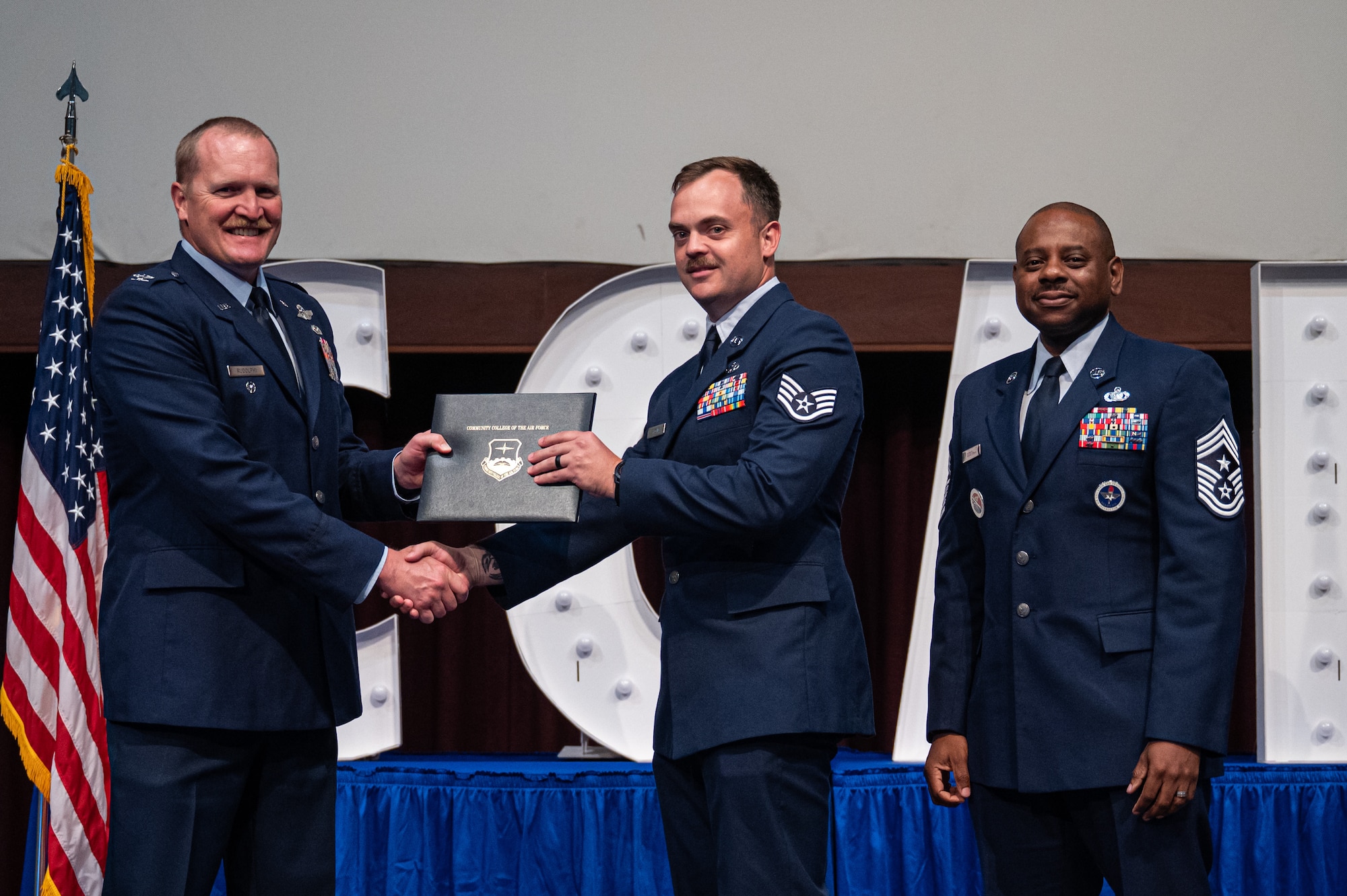U.S. Air Force Staff Sgt. Preston Higgins, Community College of the Air Force, receives his diploma from Col. Adam Rudolphi, left, 42d Air Base Wing deputy commander and Chief Master Sgt. Demetrius Booth, 42d ABW command chief during a Community College of the Air Force graduation at Gunter Annex, Alabama, May 28, 2026.
