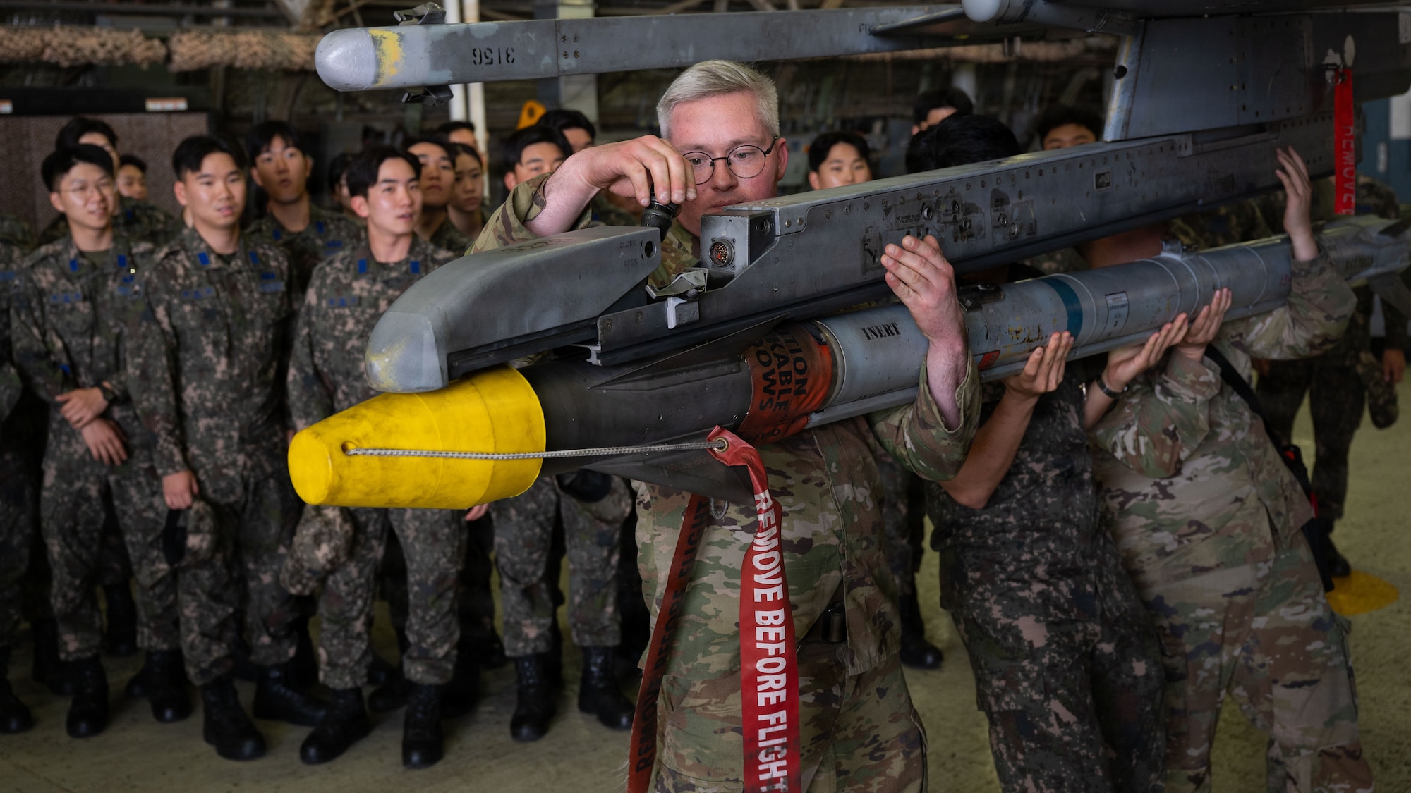 Man wearing glasses touches the weapon system of an F-16