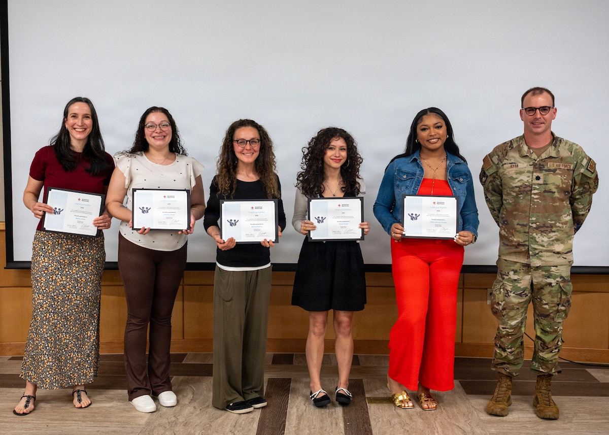Group of people hold certificates next to a uniformed member in glasses